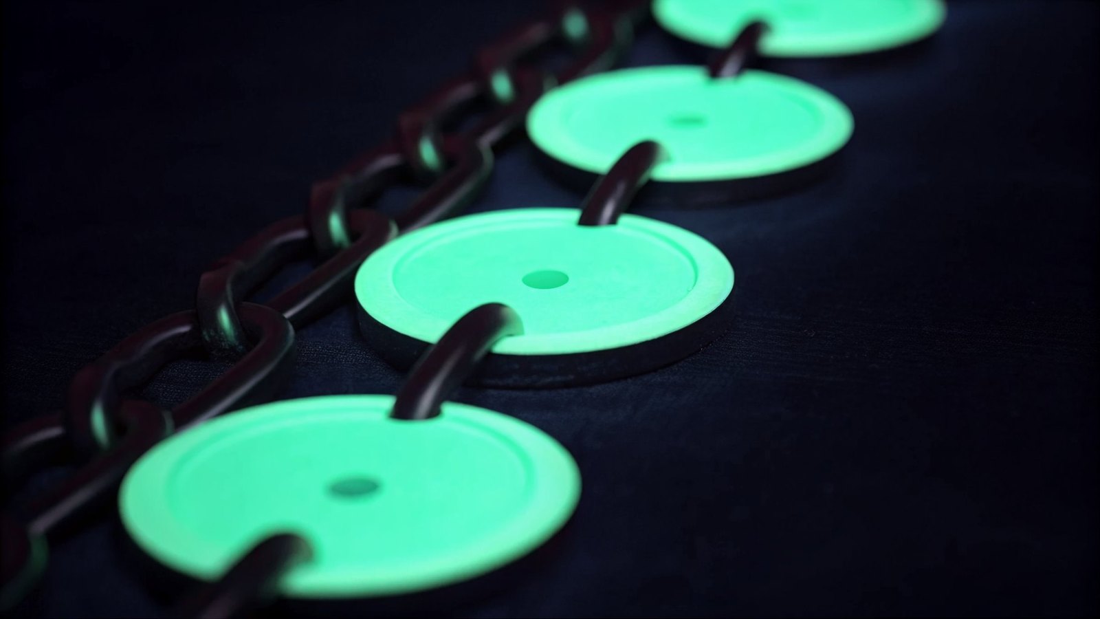 A row of wax-sealed receipt discs threaded onto a chain on a dark surface, each seal glowing emerald green, an unbroken chain of custody